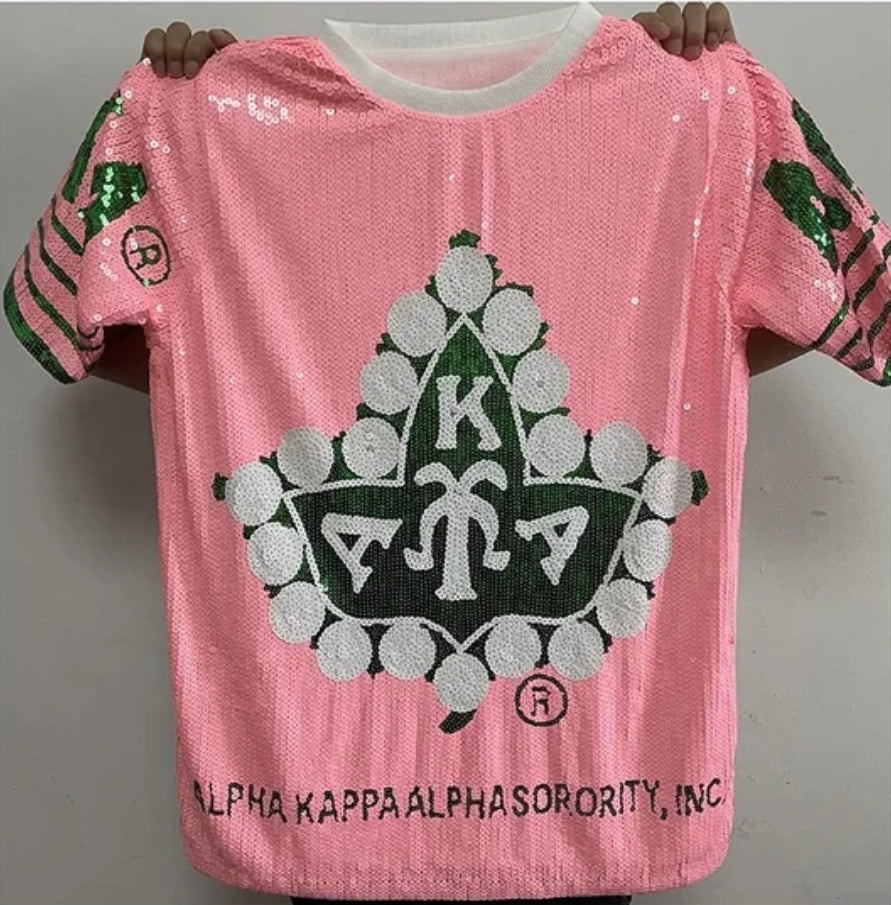 Alpha Kappa Alpha sorority sequence dress in pink, featuring a large graphic symbol.